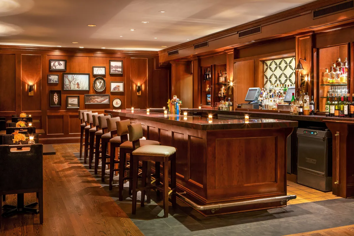 A sophisticated interior bar scene, highlighted by a stylish bar counter, comfortable seating area, and tasteful decorative wall art. The mood is upscale yet approachable, perfect for special celebrations or casual meet-ups.